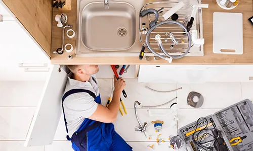 technician repairing plumbing issues in kitchen
