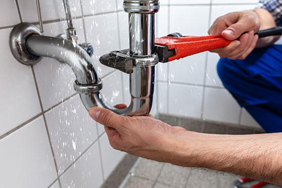 plumber fixing leaky pipe